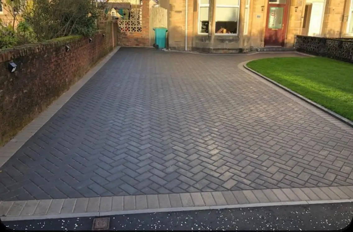 Grey monoblock (block paving) driveway laid outside a traditional sandstone house
