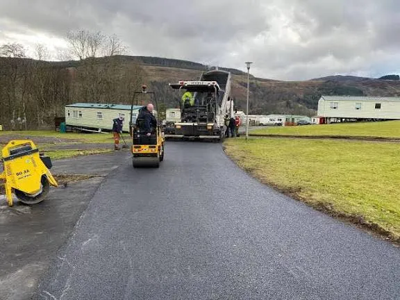 Machine-laid tarmac path being rolled at a caravan park