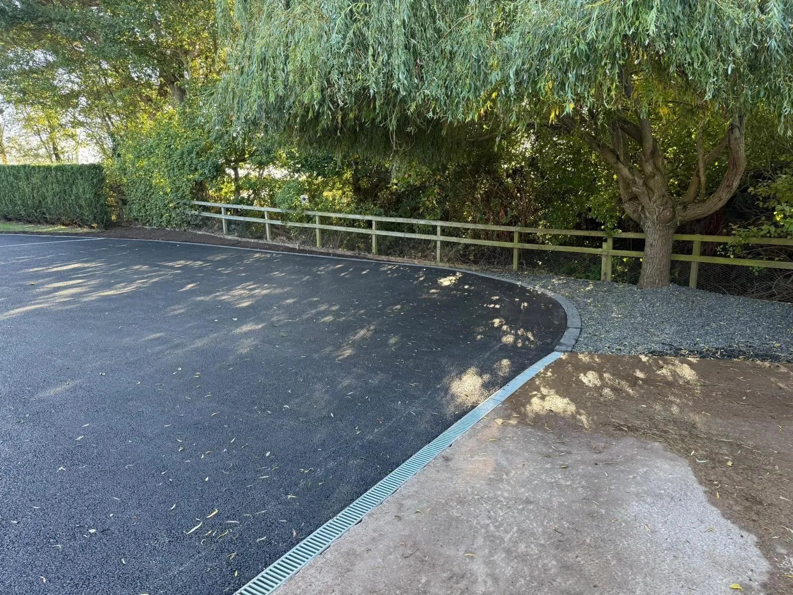 Tarmac driveway edge finished with block edging and a channel drain beside a gravel border in Edinburgh