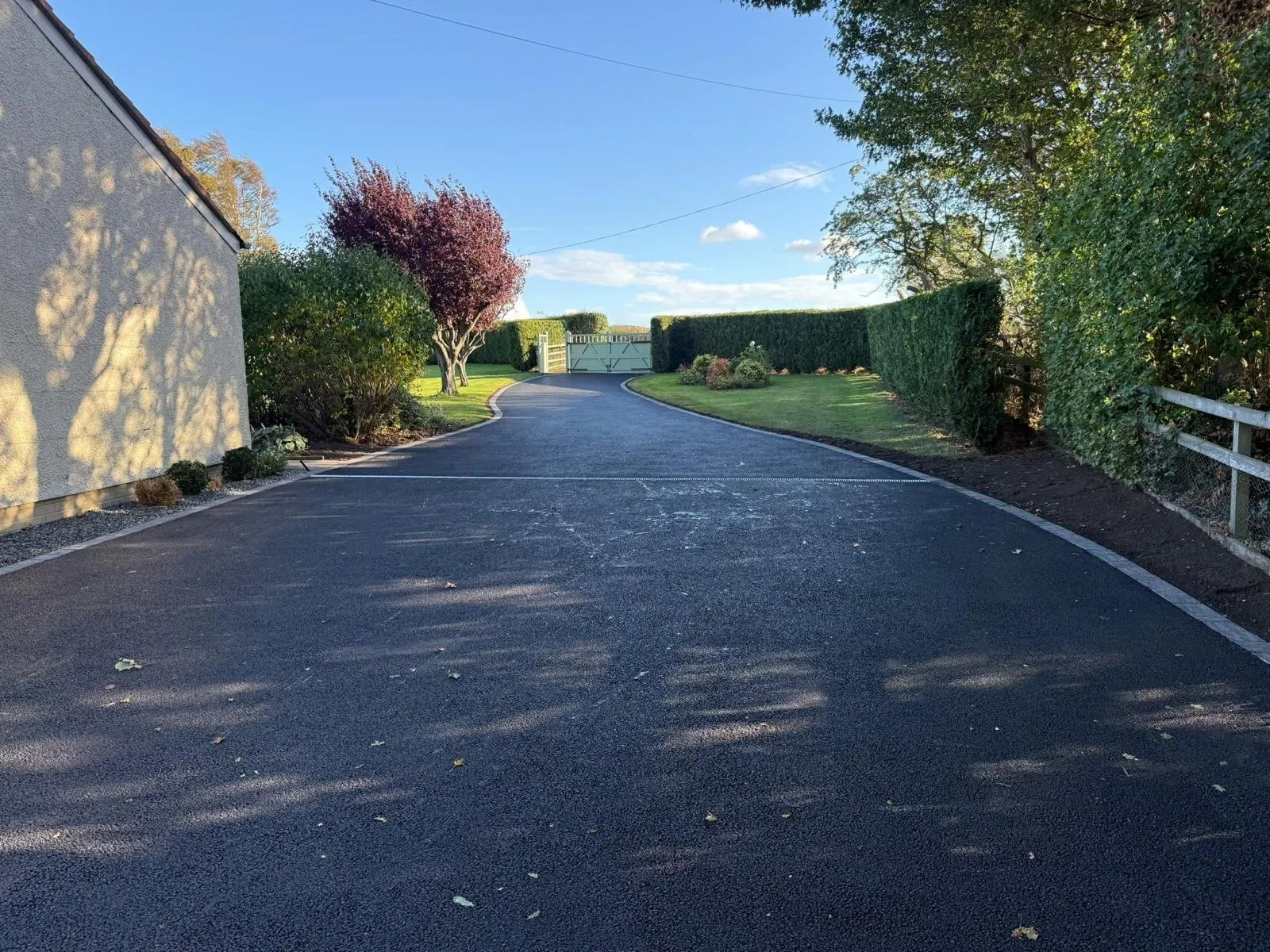 Long tarmac driveway leading up to timber gates, laid by E. Young Surfacing in Edinburgh