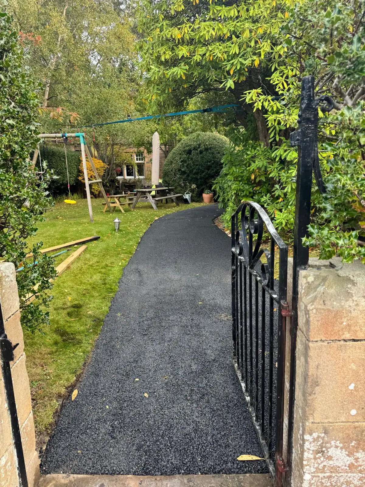 Tarmac garden path leading in from a wrought-iron gate