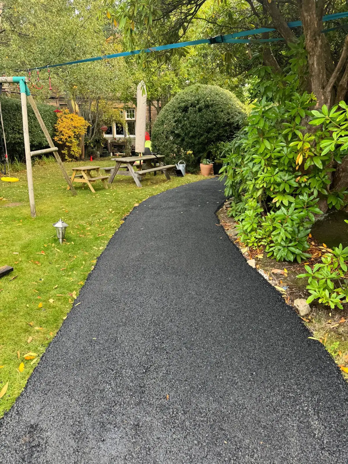 Smooth machine-laid tarmac path through a back garden