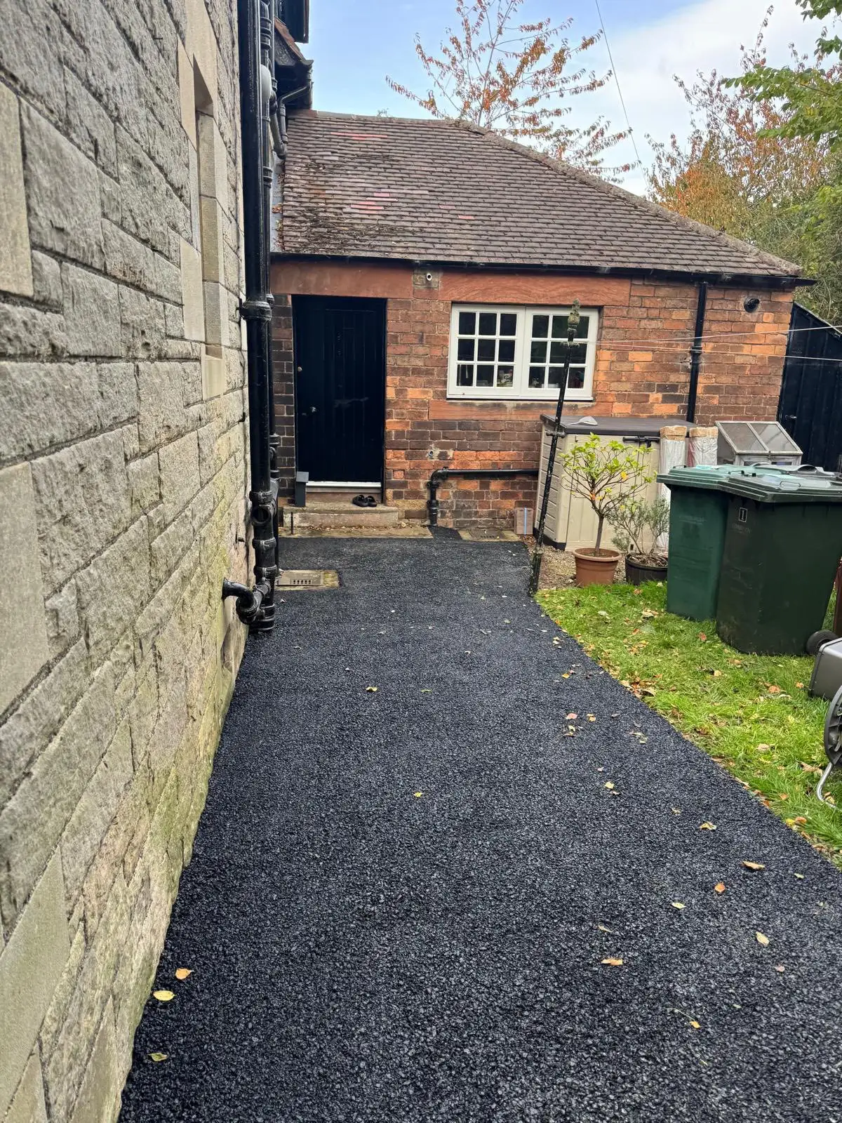 Narrow tarmac side-access path between a house and garden
