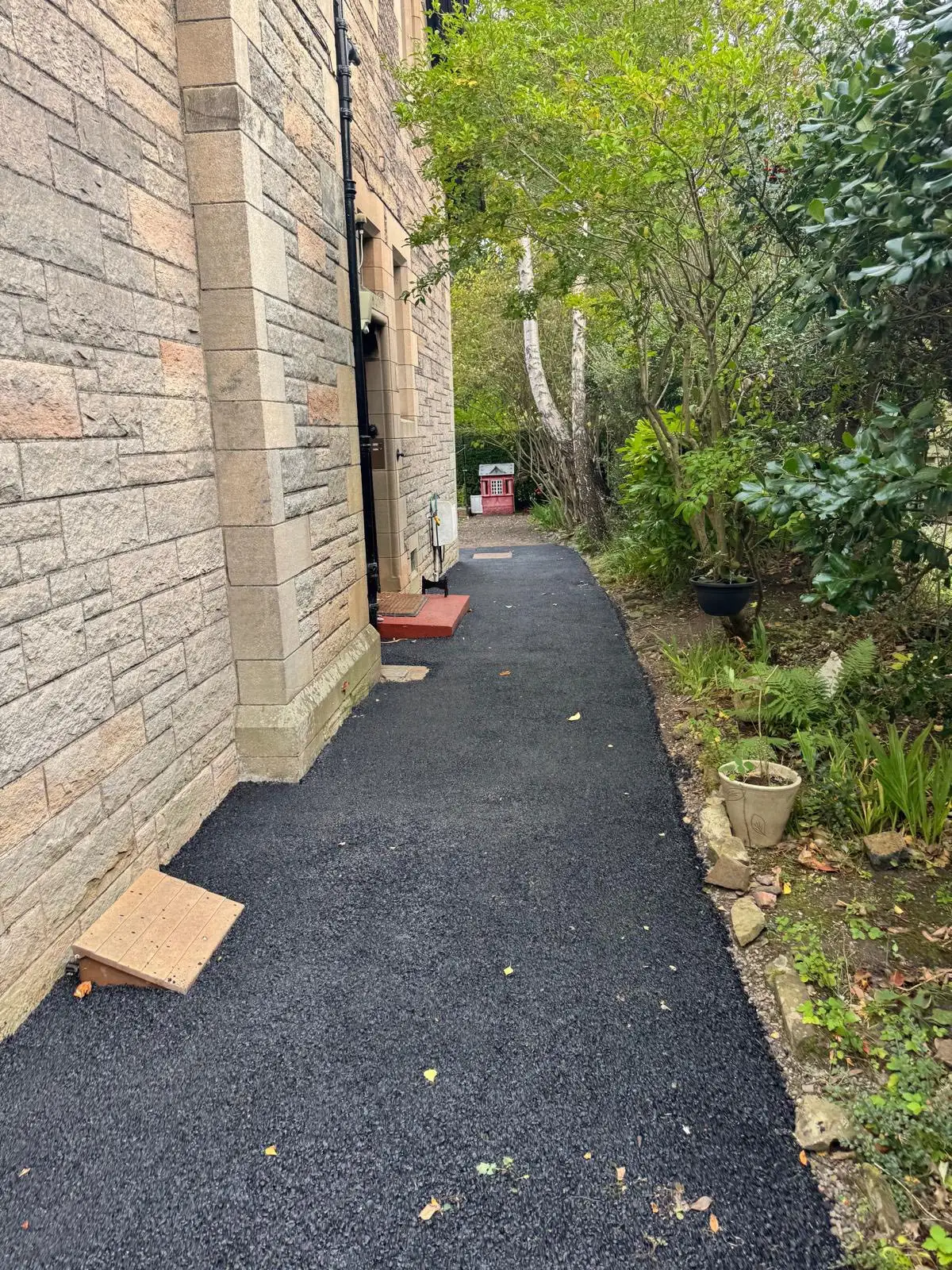Tarmac side path beside a sandstone property