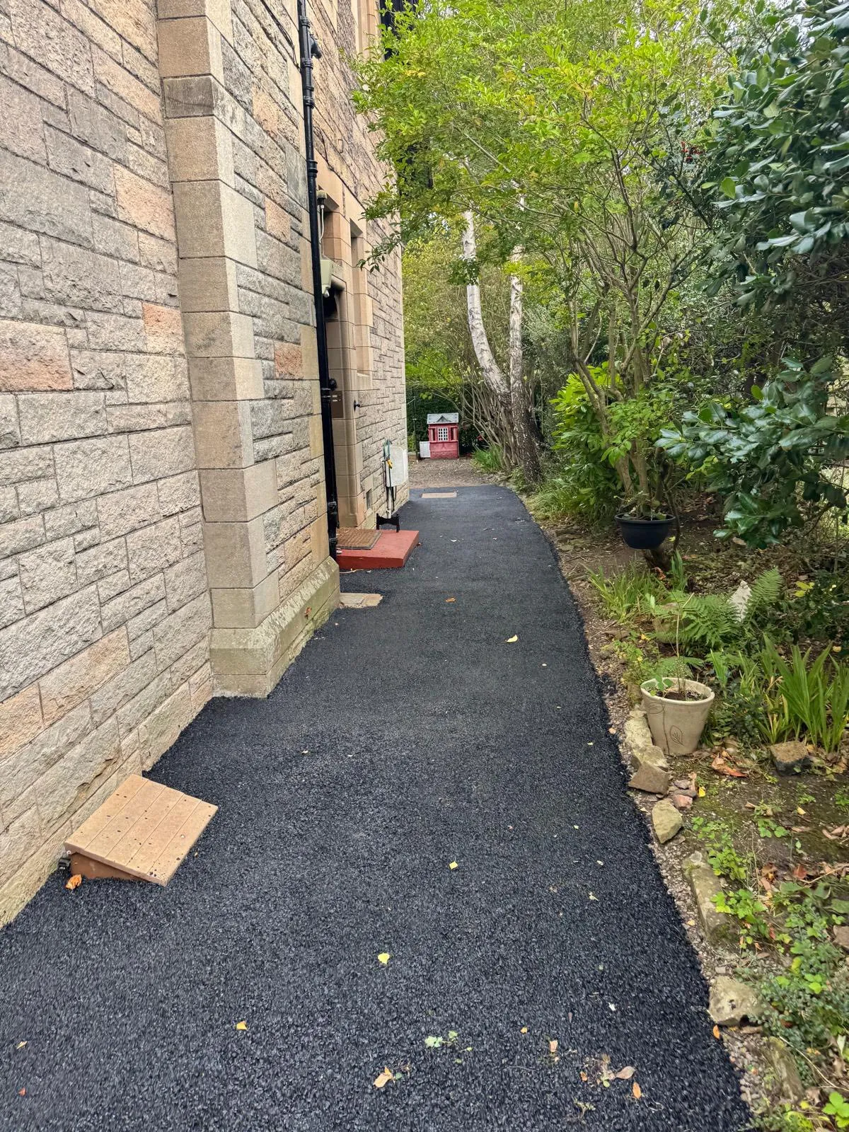 Tarmac side path beside a sandstone property